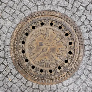Sewer cover of Berliner Wasserbetriebe with architectural sights of the capital