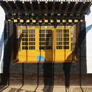 Shadows of prayer flags against the colorful windows and wall of the Pemayagtse buddhist monastery in Pelling