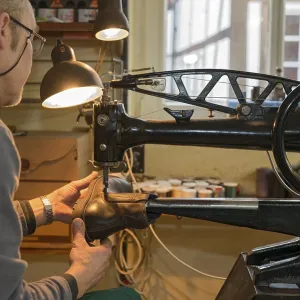 Shoemaker, shoemaker sews shoe to machine