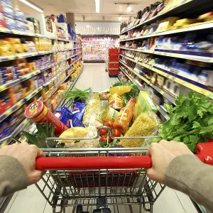 Full shopping trolley being pushed down the aisle