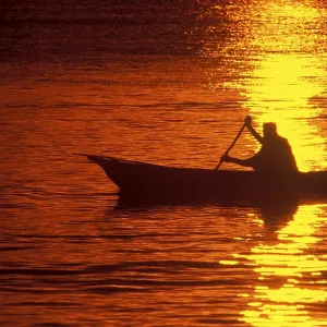Silhouette of a fisherman in his boat at sunrise near Mikadi Beach