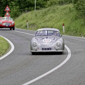 Silver-grey vintage car with racing number on a winding country road Silver-grey vintage car with racing number on a winding country road