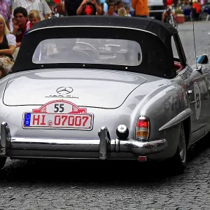 Un coche clásico convertible Mercedes de plata circula por una carretera concurrida. Un coche clásico convertible Mercedes de plata circula por una carretera concurrida.
