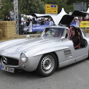 A silver Mercedes classic car with gullwing doors and starting number 417 at a festival A silver Mercedes classic car with gullwing doors and starting number 417 at a festival