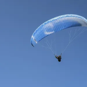 Single paraglider in the blue sky symbolizing freedom and adventure Single paraglider in the blue sky symbolizing freedom and adventure