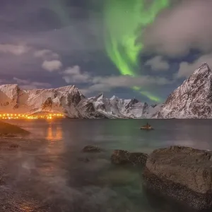 Small aurora with clouds, rocks by the ocean