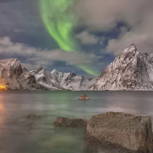 Small aurora with clouds, rocks by the ocean