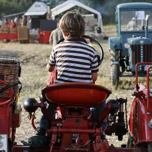 Small boy sitting at the wheel of a vintage tractor Small boy sitting at the wheel of a vintage tractor