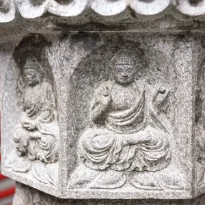 Small Buddha relief on stone lantern pedestal near the temple Small Buddha relief on stone lantern pedestal near the temple