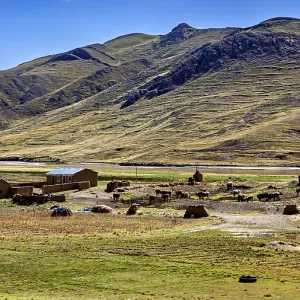 Small houses at the foot of mountains in a vast landscape under blue sky
