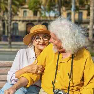 Smiling senior woman embracing her husband on a bench Smiling senior woman embracing her husband on a bench