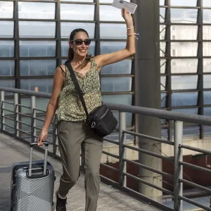 Smiling woman traveler pulling suitcase