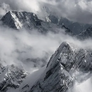 Snow-capped mountains and clouds create a dramatic atmosphere