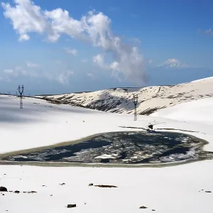 Snow-covered landscape with frozen lake and clear blue sky