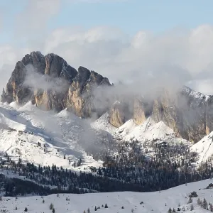 Sommet de montagnes recouvertes de neige avec des nuages roulant au-dessus dans un paysage d'hiver serein.