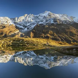 Snow-covered mountains reflected in mountain lake Snow-covered mountains reflected in mountain lake