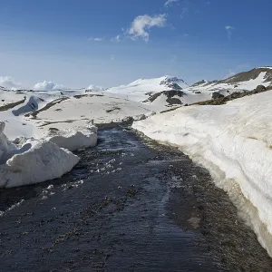 Snow-covered mountains with a road in the foreground under a clear blue sky