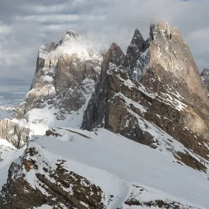 Snow-covered mountains rose majestically in the cloudy sky