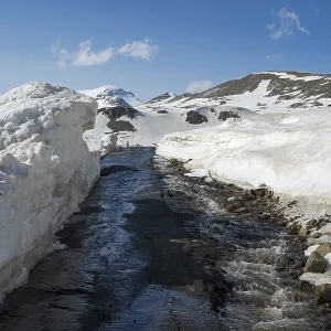 Snow-covered region with a small watercourse and road