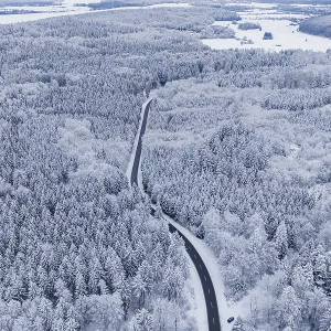 Snow-covered road leads through a vast winter forest
