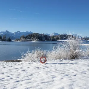 Snow-covered shore with view of snowy mountains through clear sky