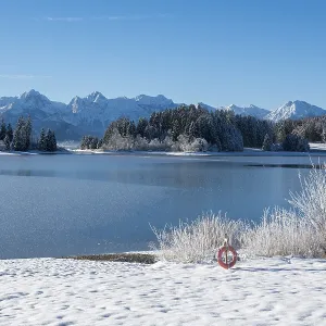 Snowy lake with mountains in the background under blue sky