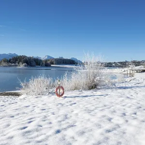 Snowy lakeside landscape with views of mountains and clear skies