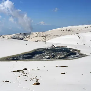 Snowy landscape with frozen lake and light blue sky