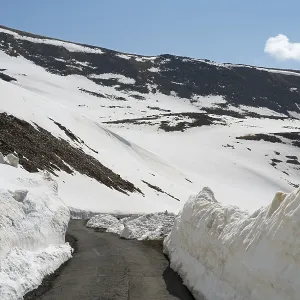 Snowy mountain landscape with snow-covered road and blue sky