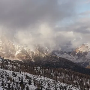 Montagnes enneigées sous un ciel nuageux avec des rayons de soleil éclatés.