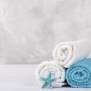 Spa composition with white and blue soft rolled cotton towels and star fish copy space