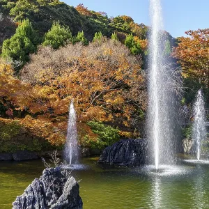 Sparkling water fountains in a Japanese garden with autumn trees and rocks
