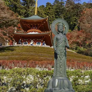 Spiritual image of a Buddha statue in front of a temple surrounded by autumn trees