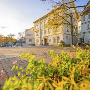 Square with historic building and blooming plants in the foreground in autumn sunshine Square with historic building and blooming plants in the foreground in autumn sunshine