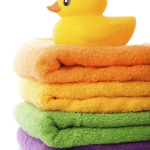 Stack of colorfull towels and yellow rubber duck isolated on white