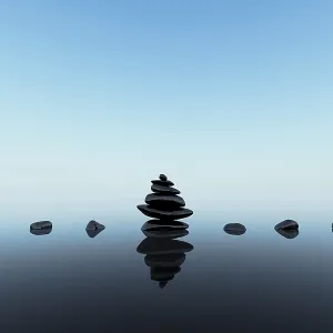 Stacked black stones with reflections on blue clean background Stacked black stones with reflections on blue clean background