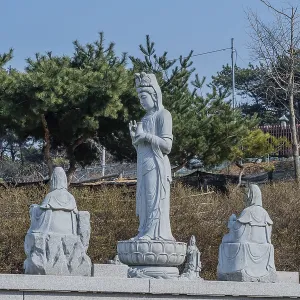 Standing stone carved Buddha in prayer under blue sky in Pyeongtaek Standing stone carved Buddha in prayer under blue sky in Pyeongtaek