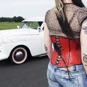 Starter girl with a red corsage and tattoos next to a white limousine