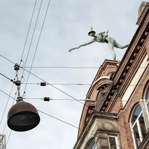 A statue atop a historic building against a backdrop of a clear sky with suspended cables A statue atop a historic building against a backdrop of a clear sky with suspended cables