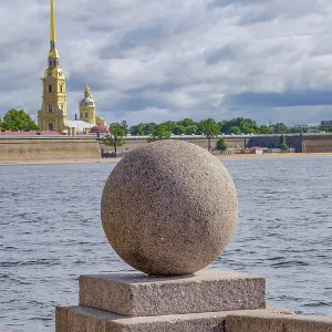 Stone ball on the river with cathedral in the background under a cloudy sky