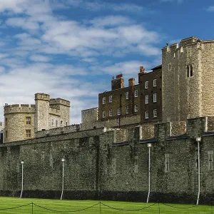 Stone fortress with green lawn under a bright blue sky with clouds at The Tower of London