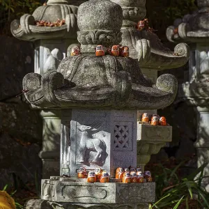 Stone lanterns decorated with small figures stand in a Japanese garden