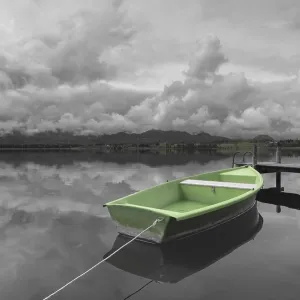 Storm clouds at sunset, a green rowing boat lashed to the wooden jetty