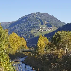 A stream snakes through an autumnal valley
