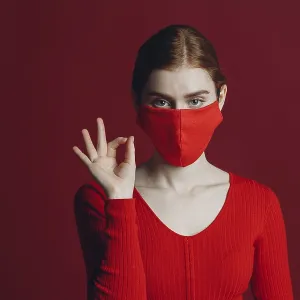 Studio portrait ok sign of young woman in protective medical face mask isolated on red background Studio portrait ok sign of young woman in protective medical face mask isolated on red background