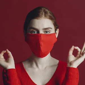 Studio portrait of young woman in protective medical face mask isolated on red background Studio portrait of young woman in protective medical face mask isolated on red background
