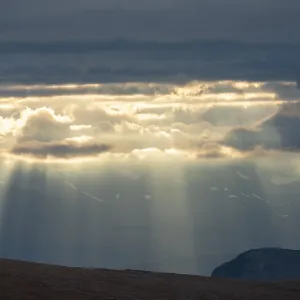 Sun rays fall through clouds in mountain landscape Sun rays fall through clouds in mountain landscape