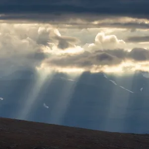 Sun rays fall through clouds in mountain landscape Sun rays fall through clouds in mountain landscape