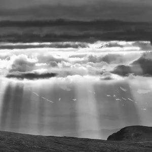 Sun rays fall through clouds in mountain landscape Sun rays fall through clouds in mountain landscape