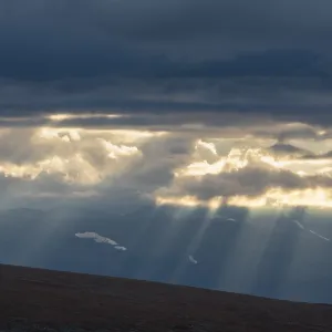 Sun rays fall through clouds in mountain landscape Sun rays fall through clouds in mountain landscape